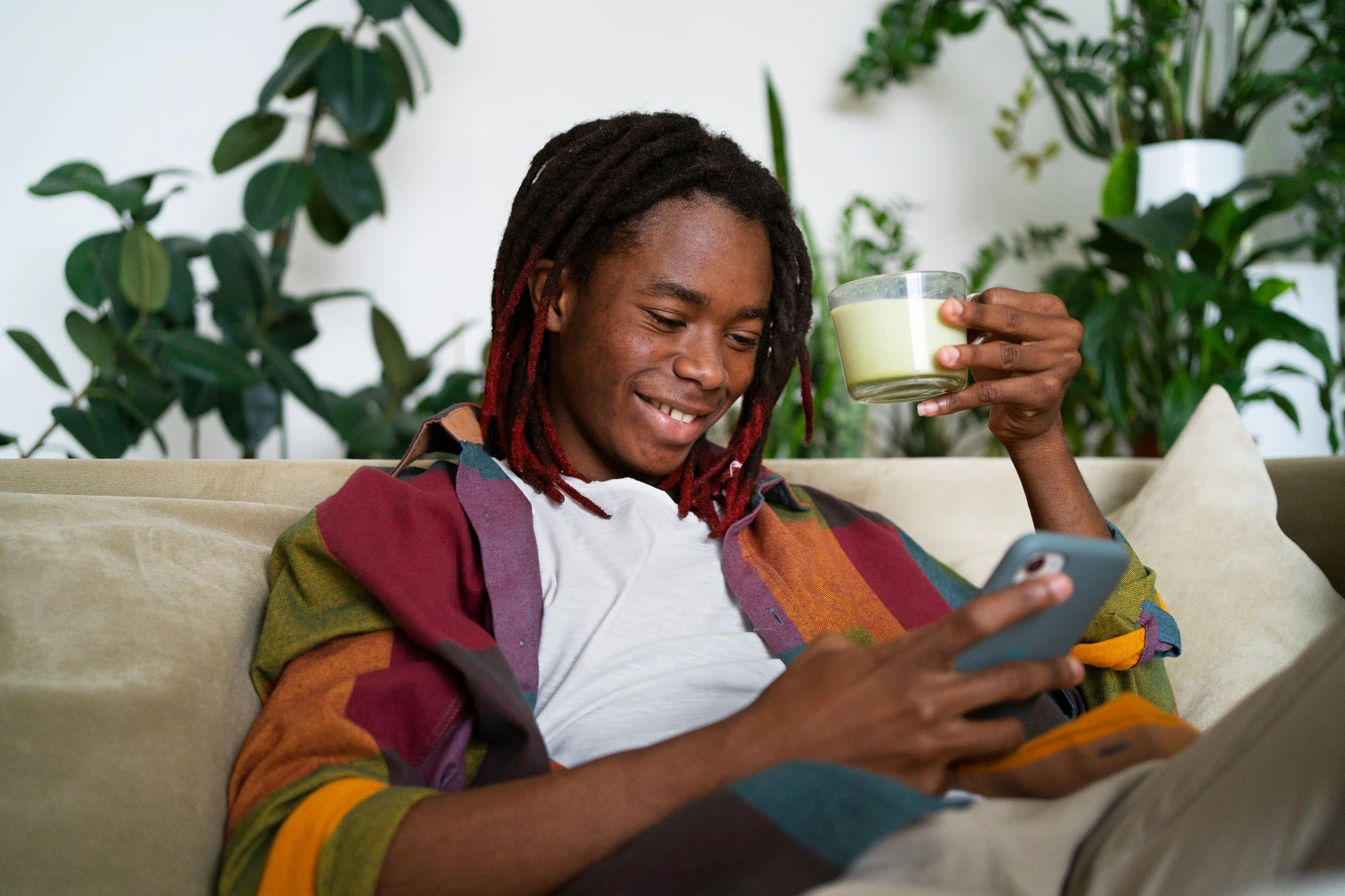 Un jeune homme révise le code sur son téléphone, installé dans son canapé
